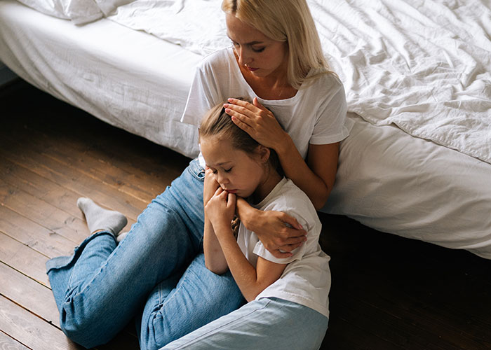 Woman comforting a distressed child sitting on the floor in a house, reflecting tenant concerns about living conditions.