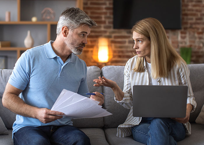 Man inheriting house discussing tenant concerns about making the living environment terrifying on a couch at home.