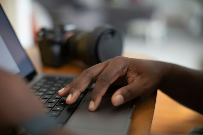 Close-up of a person’s hand typing on a laptop keyboard with a camera in the background, illustrating scary online moments.