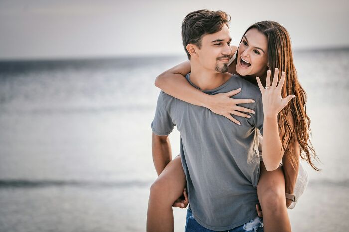 Couple on the beach with woman showing engagement ring, illustrating emotional moments in epicly unhinged ways people got back at cheating exes.