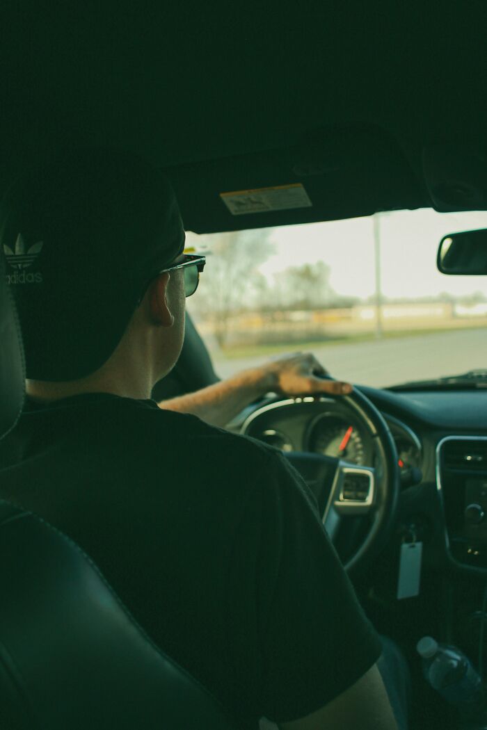 Man wearing sunglasses and a cap driving a car, illustrating awkward moments when nice guys turned creepy.