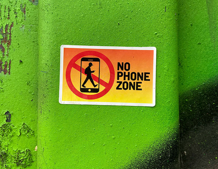 No phone zone sign on a green wall, illustrating rules Jeff Bezos and Lauren Sánchez enforce for Venice wedding guests. No phone zone sign on a green wall, illustrating rules Jeff Bezos and Lauren Sánchez enforce for Venice wedding guests.