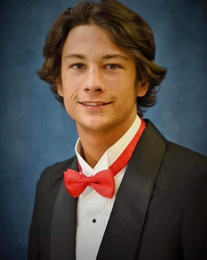 Teen in formal suit with red bow tie smiling against a blue background related to family lawsuit and suspects. Teen in formal suit with red bow tie smiling against a blue background related to family lawsuit and suspects.