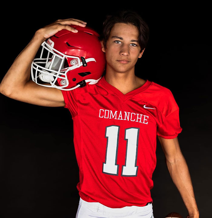 Teen football player in red Comanche jersey holding helmet, related to family lawsuit in teen corpse case. Teen football player in red Comanche jersey holding helmet, related to family lawsuit in teen corpse case.