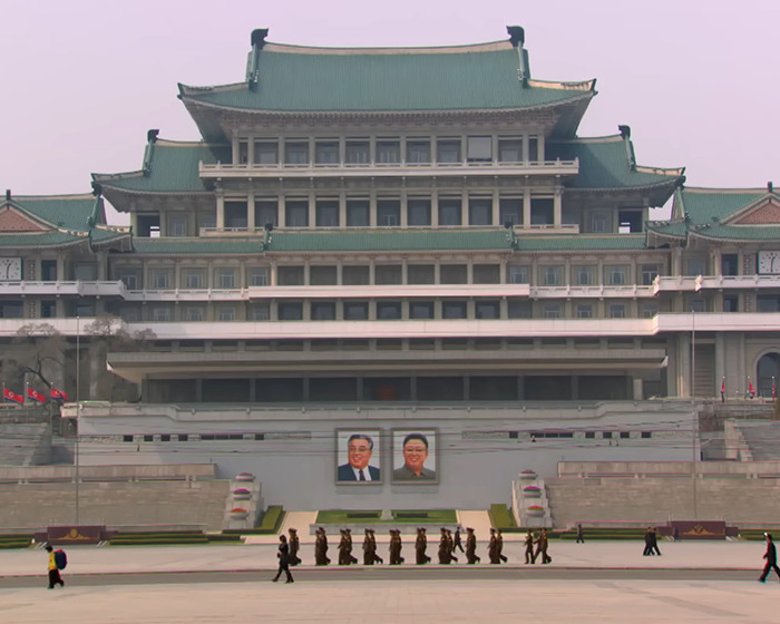 North Korean building with portraits of leaders and people walking, illustrating control measures using smuggled smartphones.