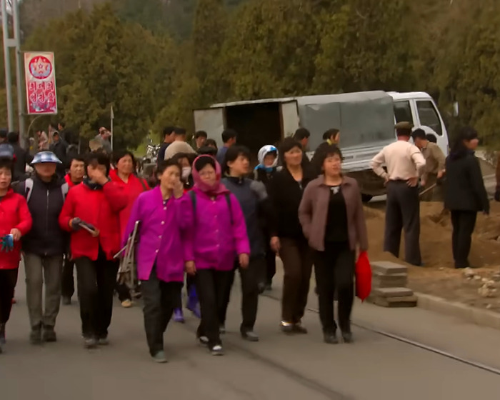 A group of North Korean people walking on a street near a truck, illustrating control measures under Kim Jong Un.