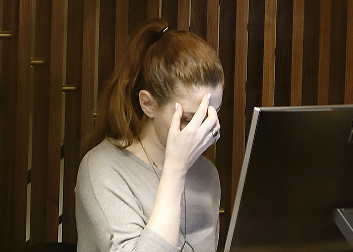 Woman at computer covering face with hand showing frustration, illustrating not in job description petty revenge concept.