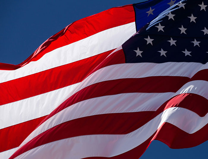 Close-up of the American flag waving against a clear blue sky representing legal claims and law discussions.