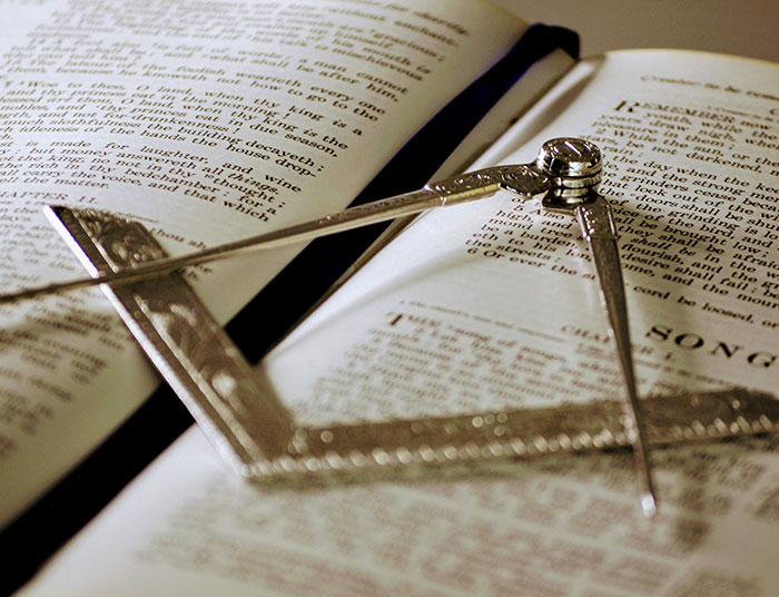Antique metal compass and square resting on the pages of an open legal book, symbolizing legal claims and law.