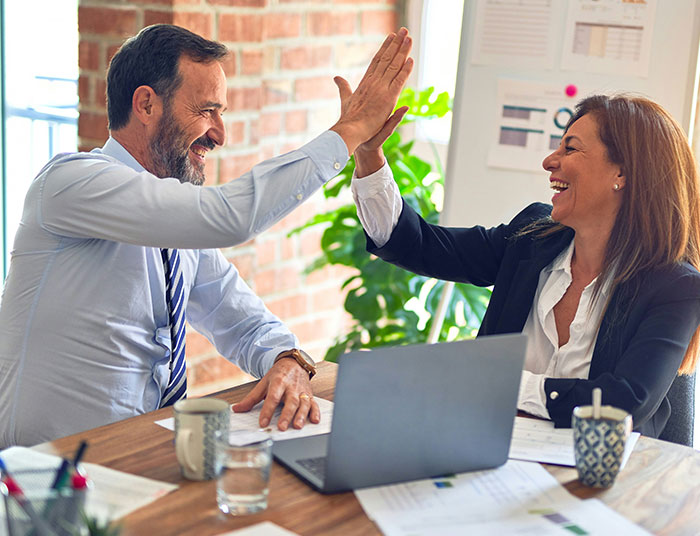 Two business professionals smiling and high-fiving in an office, illustrating absurd legal claims discussion.