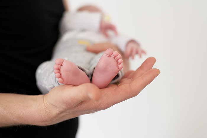 Healthcare worker holding tiny baby feet gently in hand, symbolizing impactful moments in healthcare care.