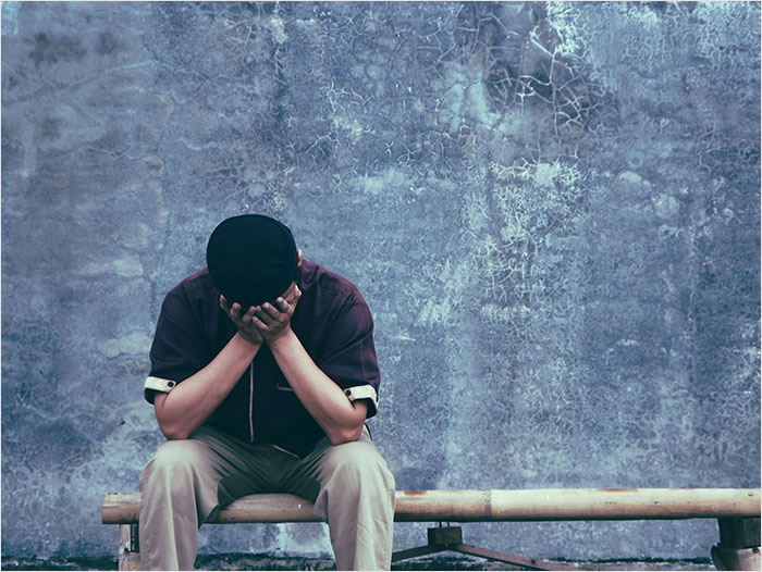 Healthcare worker sitting on a bench, covering face with hands, showing emotional struggle and impact on healthcare workers.