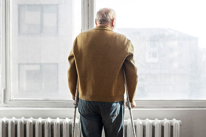 Elderly man on crutches looking out a window, reflecting a moment that changed healthcare workers forever.