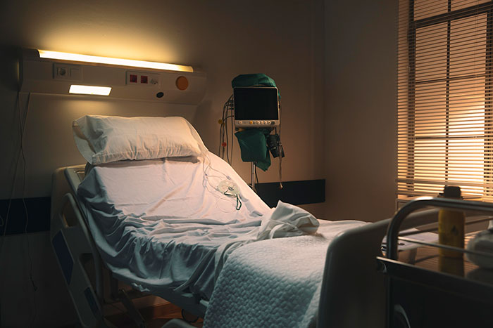 Empty hospital bed with medical equipment in a dimly lit room, reflecting moments that changed healthcare workers forever.