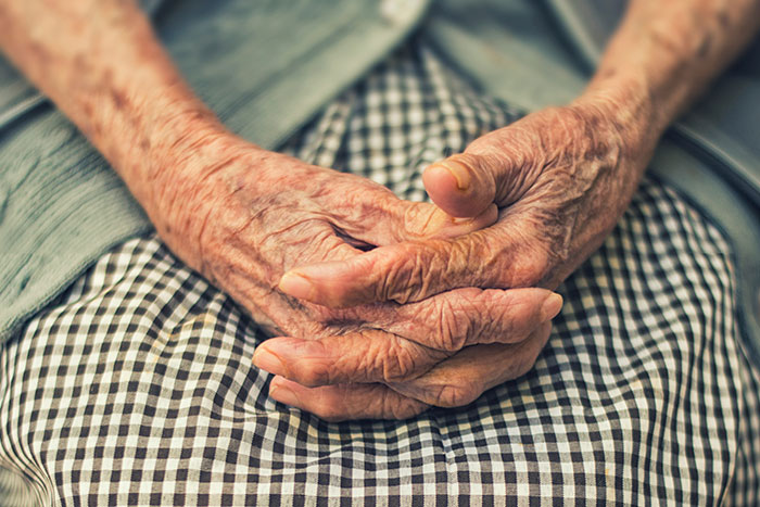 Wrinkled elderly hands resting on a checkered skirt, symbolizing moments that changed healthcare workers forever.
