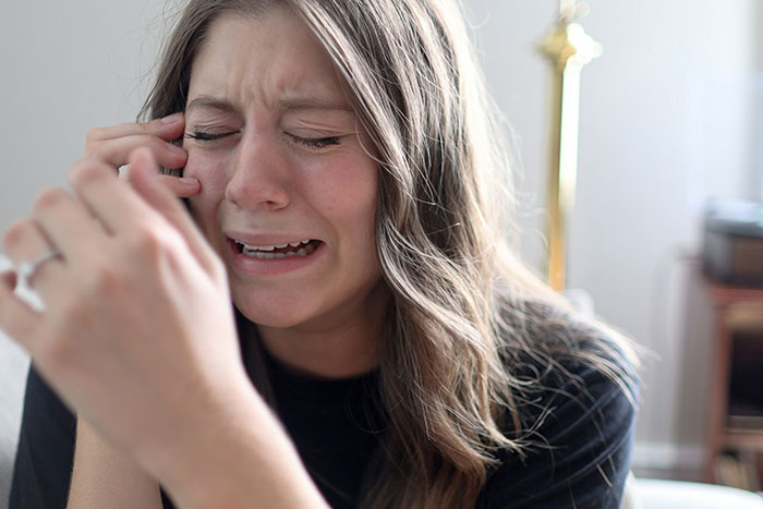A distressed woman crying indoors, capturing the emotional impact on healthcare workers during unforgettable moments.