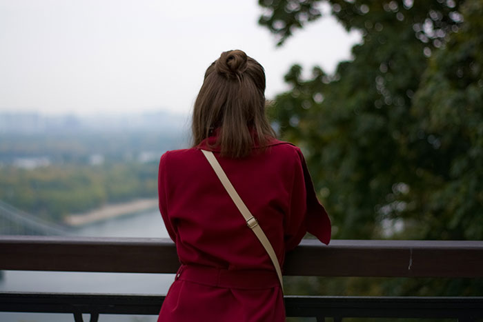 Person in a red coat overlooking a river, reflecting on moments that changed healthcare workers forever.