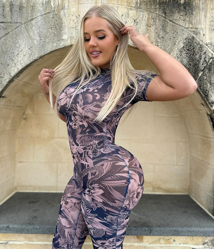 Woman posing outdoors wearing a patterned bodysuit, highlighting her figure after getting BBL cosmetic surgery.