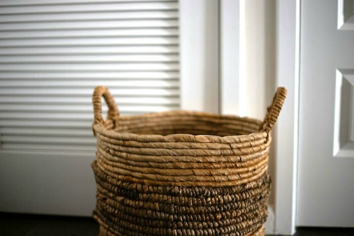 Woven storage basket sitting on floor near white closet doors among everyday items under 300 dollars improving lives.