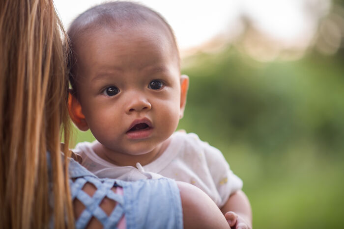 Baby being held outdoors, with focus on the child’s face, related to one mississippi counting countries concept.