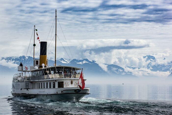 Steamboat sailing on calm waters with snowy mountains in the background, illustrating one Mississippi counting countries.