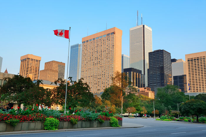 City skyline with Canadian flag and vibrant flowerbeds, representing one Mississippi counting countries in an urban setting.