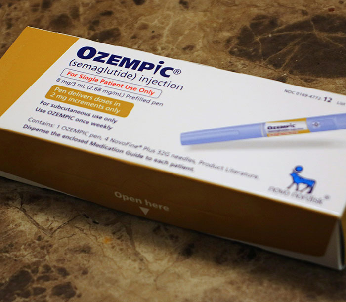 Ozempic medication box and injection pen, highlighting concerns about Ozempic hands side effect by doctors.