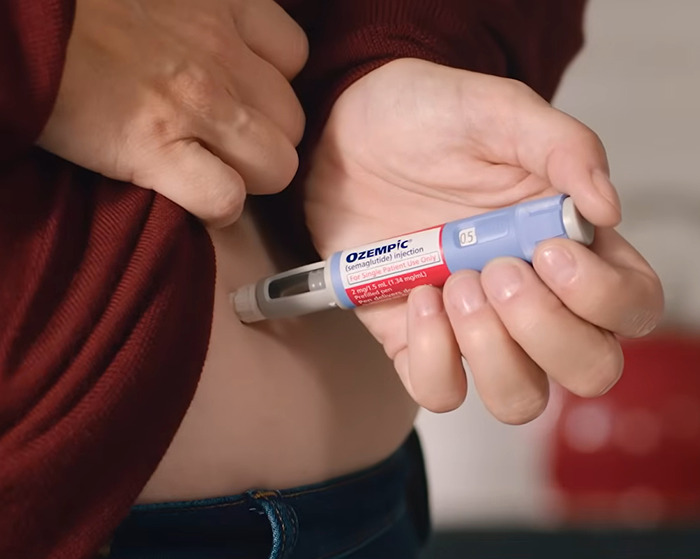 Person using Ozempic injection pen on abdomen, highlighting concerns about organ-damaging effects of Ozempic and Mounjaro.
