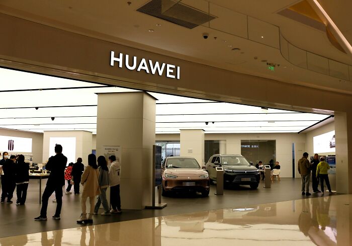 Interior view of Huawei store with customers, showcasing products and technology in a modern retail space.