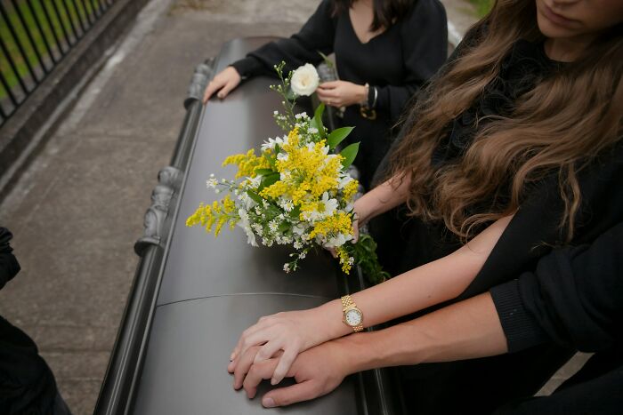 Two women in black mourning clothes holding hands and flowers at a funeral, symbolizing revenge against cheating exes.