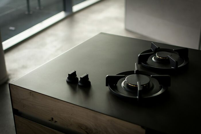 Modern black gas stove with two burners and control knobs on a sleek kitchen counter, representing epic unhinged revenge.