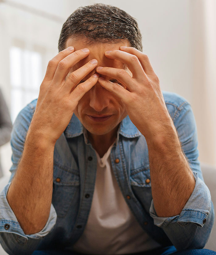 Stressed man in a denim jacket holding his forehead, illustrating parents who disowned their children emotionally.