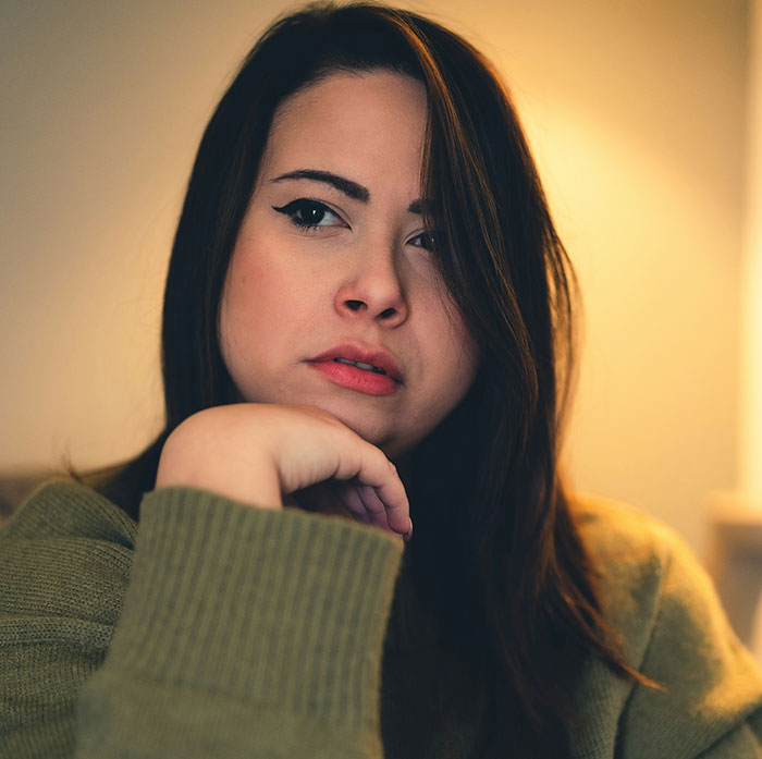 Young woman in a green sweater with thoughtful expression, illustrating parents who disowned their children choices.