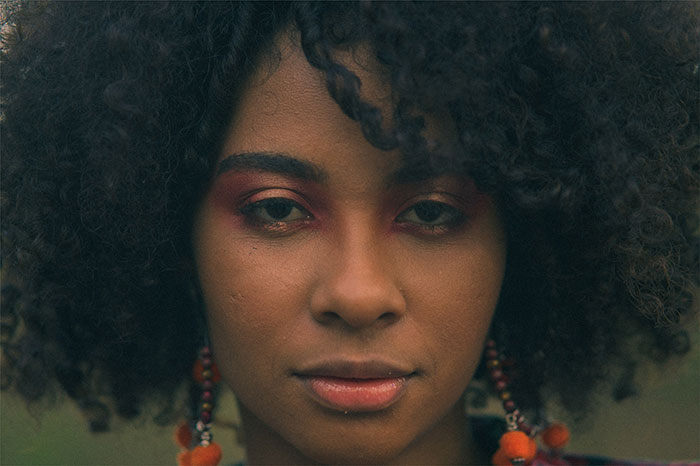 Close-up of a woman with curly hair and colorful earrings, reflecting emotions related to parents who disowned their children.