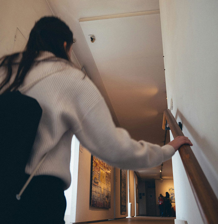 Person walking down a hallway, holding a railing, symbolizing parents who disowned their children and the reasons behind it.