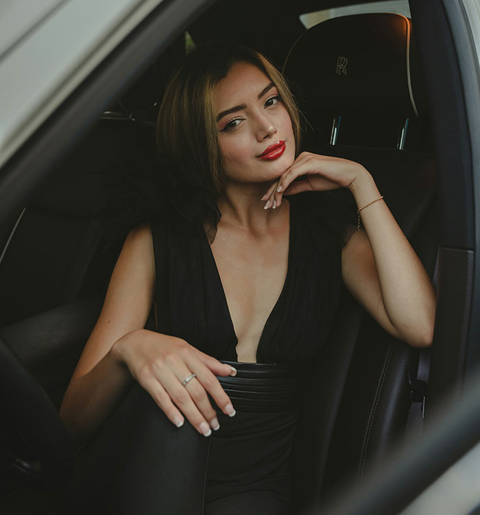 Young woman sitting in a car, looking thoughtful, representing themes of parents who disowned their children.