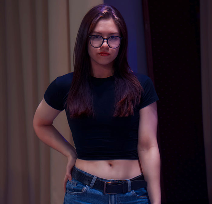 Young woman wearing glasses and casual clothes, expressing a serious mood related to parents disowning children.