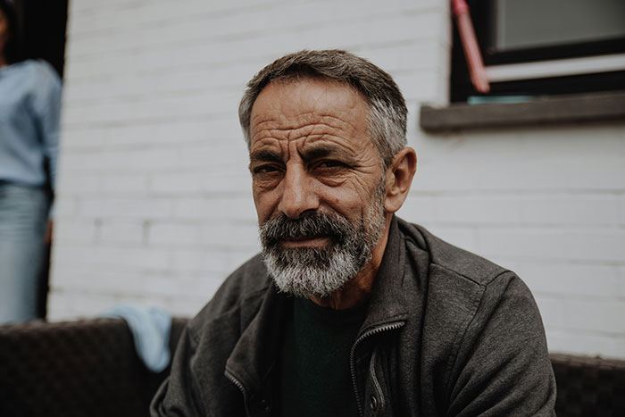 Older man with gray beard and serious expression sitting outdoors, reflecting on parents who disowned their children stories