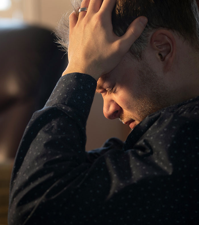 Man holding his head in distress, illustrating emotions linked to parents who disowned their children and the reasons behind it.