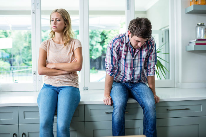 Woman and man sitting apart in kitchen looking upset, caught in bathroom together during party, tension visible Woman and man sitting apart in kitchen looking upset, caught in bathroom together during party, tension visible