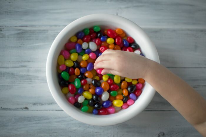 A hand reaching into a bowl filled with colorful jelly beans, symbolizing women over 42 no longer tolerating limits.