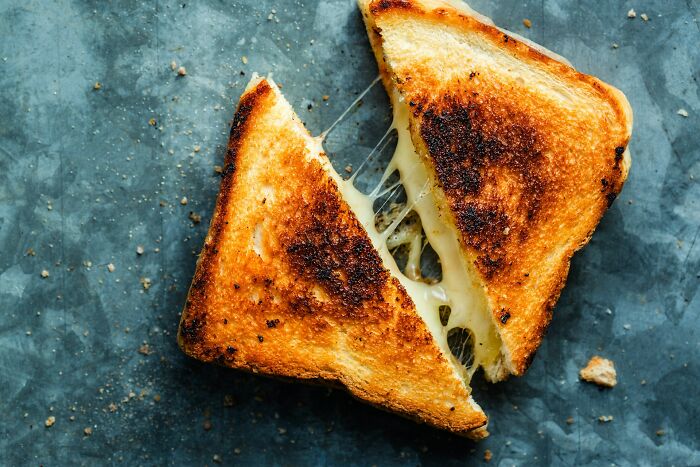 Toasted sandwich cut in half with melted cheese stretching between, illustrating a misconception about pregnancy with twins.