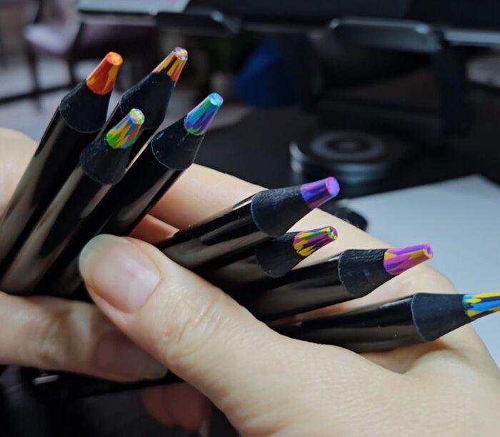Hand holding multicolored artisan pencils showcasing trending products in the Pandaverse virtual marketplace.