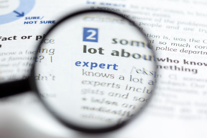 Magnifying glass highlighting the word expert on a printed page illustrating skills people online needed before the 2000s.
