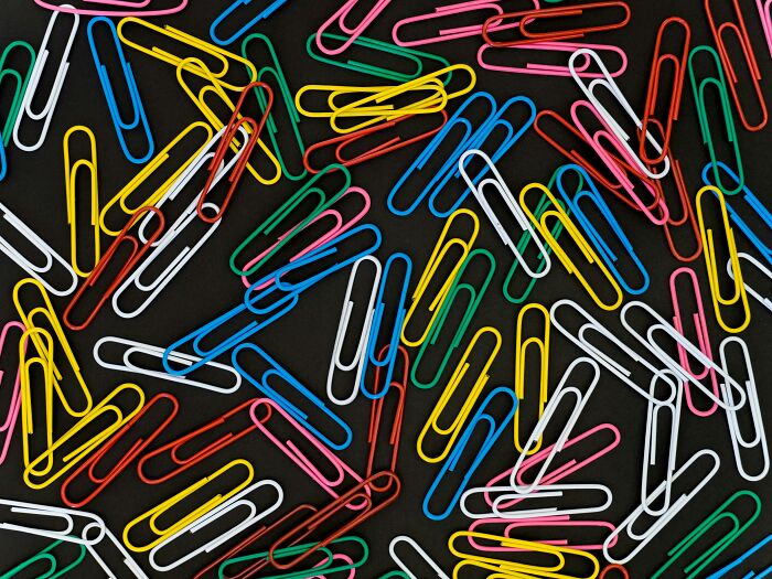 Colorful paperclips scattered on a black surface representing outdated skills people online needed before the 2000s.