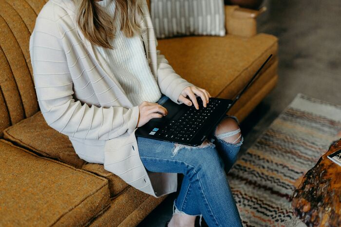 Woman sitting on a vintage couch using a laptop, representing skills people online needed before the 2000s.