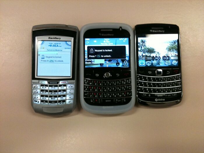 Three classic BlackBerry phones with physical keyboards, representing skills people online needed before the 2000s.