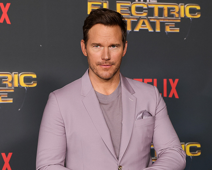 Chris Pratt posing at a premiere event, wearing a light purple blazer, sparking heated reactions online.
