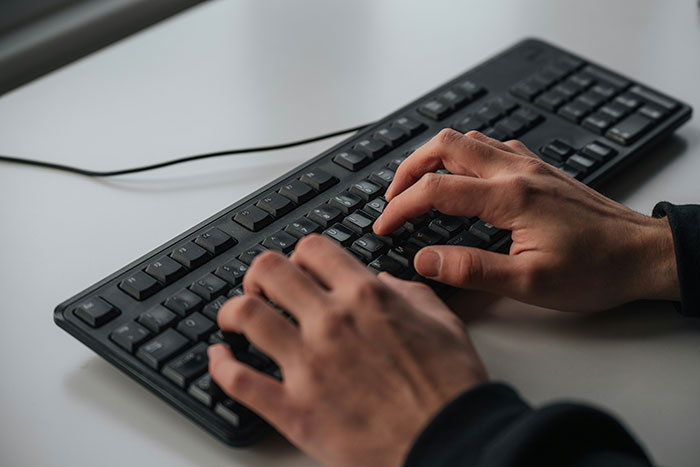 Person typing on a black keyboard, illustrating people who experienced psychosis sharing terrifying things they saw and felt.