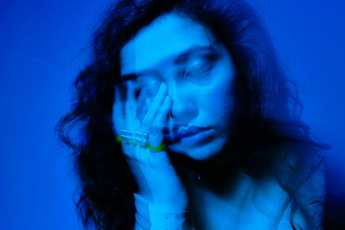 Person experiencing psychosis with blurred face and hand over eyes, conveying distress and terrifying feelings.